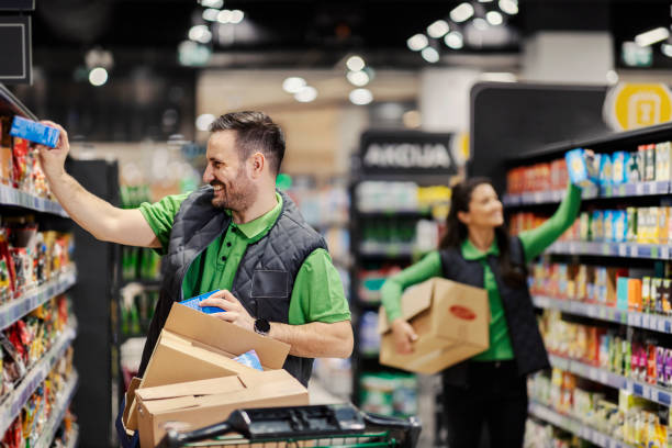 Happy employees putting groceries on shelves at supermarket.